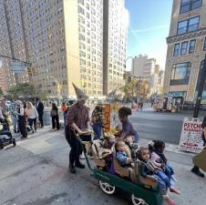 Celebrating tots getting a ride around Chelsea during the annual Buckle My Shoe Halloween parade.