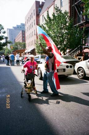 A man waves a Puerto Rican flag over an elder at the Puerto Rican Day Festival in Spanish Harlem.