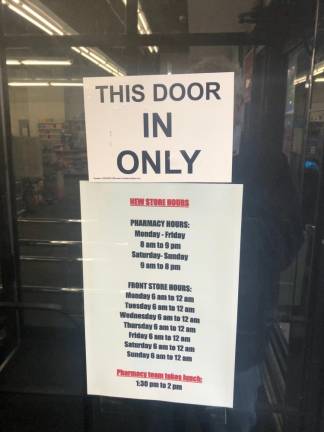 A sign on the door displays shortened operating hours. Both the pharmacy and front store had previously been open for 24 hours a day.