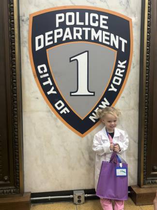 A parade goer from Epiphany school poses before the an NYPD shield in the 13th Precinct stationhouse, an annual stop on the school’s annual parade through the streets of Gramercy Park.