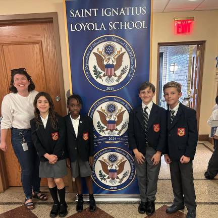 Students and a teacher stand proudly in front of the three-time-winner ribbon.