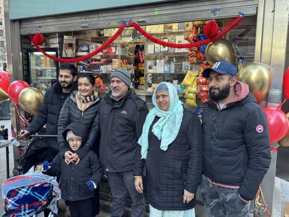 Topia, flanked by generations of his family, poses in front of his “new” newsstand.