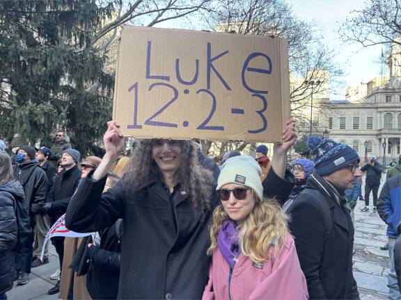 Alexander Thornton, a law clerk, holds a sign referring to a New Testament passage. Thornton attended an anti-Trump rally with Lena Nowak-Laird, a philosophy professor at the New School.