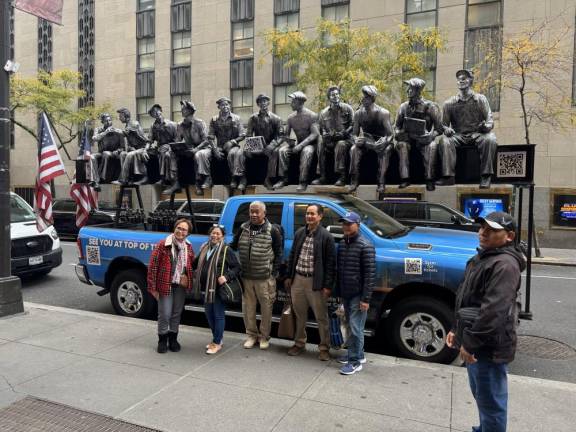 People posing in front of a replica statue of the famed “Lunch atop a Skyscraper” photo, which will be parked near 30 Rockefeller Plaza from October 30 through the end of the year.