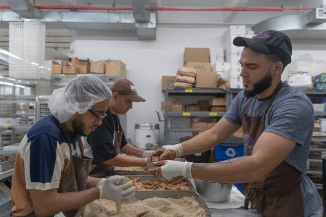 Chocolatiers Brian and Alexis dividie the dunk and dip process, with Brian coating the buttercrunch candies in melted chocolate and Alexis shuffling them in the roasted almonds mix.