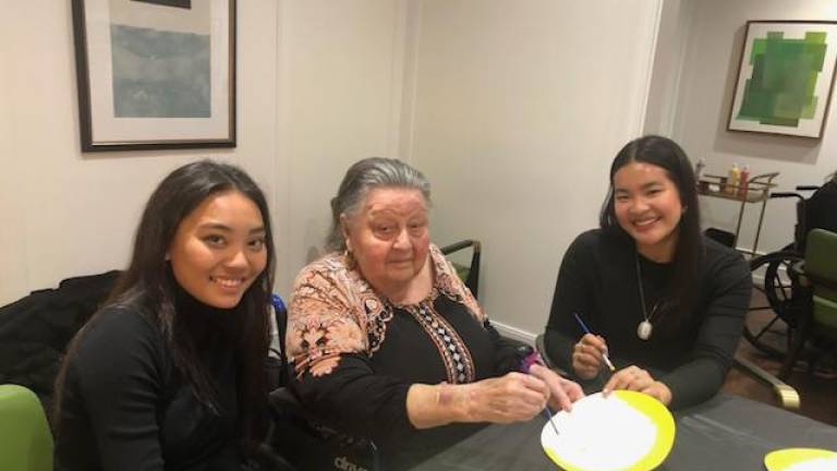 Volunteers Kaitlyn Sato and Sofia Balanay flank resident Janice Wolkenberg at Sunrise.